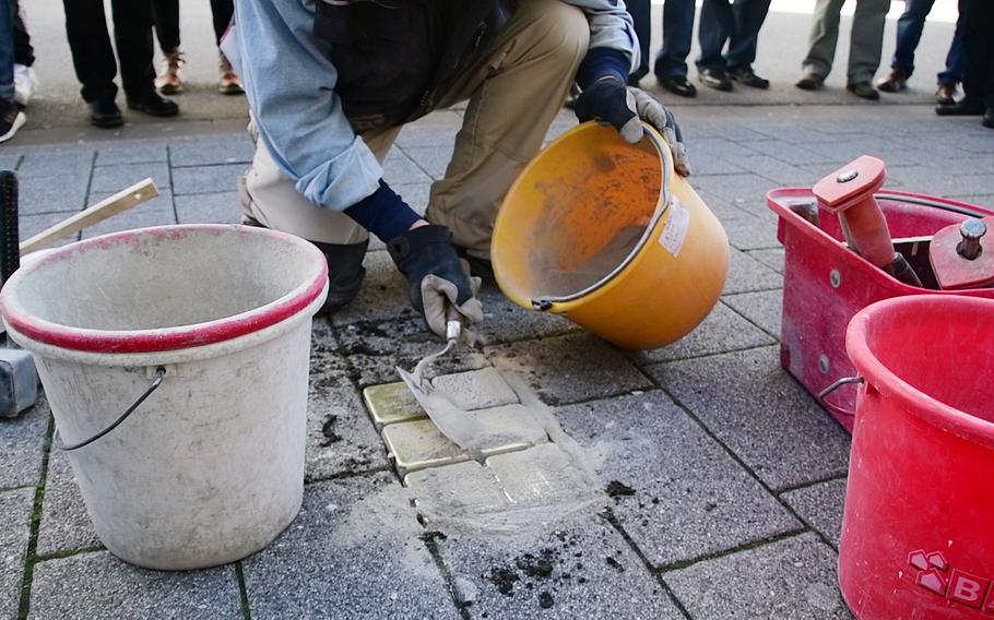 Artist Gunther Demnig applies concrete to Stolpersteine he just laid in the sidewalk on Eisenbahnstrasse in Kaiserslautern on Wednesday, February 5, 2020. The five stones outside a business in downtown Kaiserslautern memorialize Theodor and Bertha Strauss, who were killed at Treblinka death camp, built and operated by Nazi Germany in occupied Poland, and their children, who escaped to the U.S.