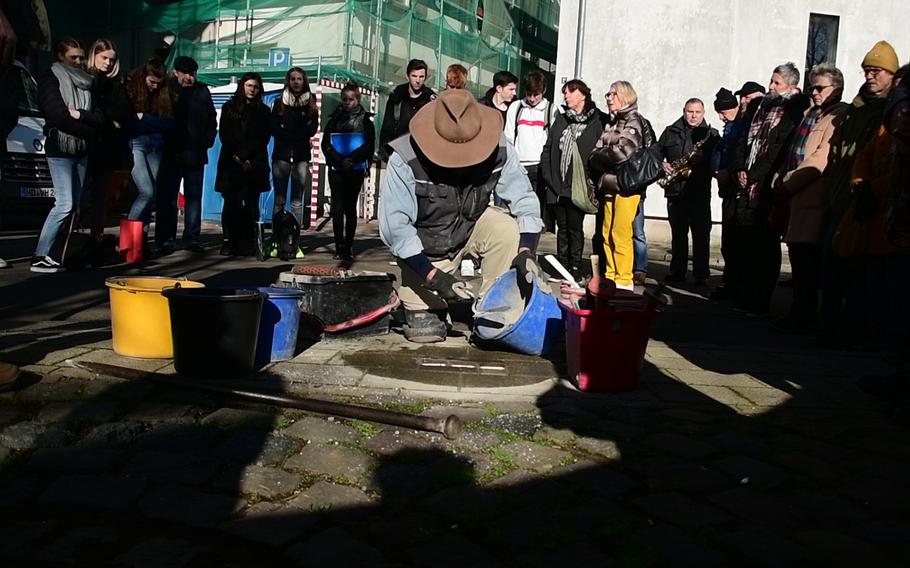 Artist Gunther Demnig applies concrete to Stolpersteine he's just laid in the sidewalk on Baumstrasse in Kaiserslautern on Wednesday, February 5, 2020. The stones memorialize the Goetz family, who fled Nazi Germany to the United States in 1935.