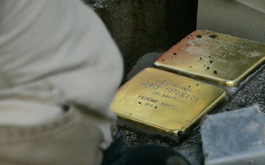 Artist Gunther Demnig kneels overthe space where he's just dug a heavy paving stone out of the sidewalk on Eisenbahnstrasse in Kaiserslautern on Wednesday, February 5, 2020, and inserted two new brass Stolpersteine remembering victims of the Nazi regime. Kaiserslautern has 152 Stolpersteine, many of them in or near the town center.