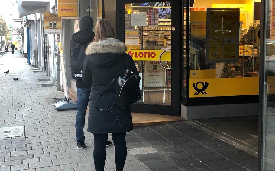 Two people stand a meter apart from each other outside a shop on Eisenbahnstrasse in Kaiserslautern, where a sign says only two customers can be inside at one time. The head of the Army's 21st Theater Sustainment Command said Friday that those who don't obey German restrictions could face government fines and military punishment.