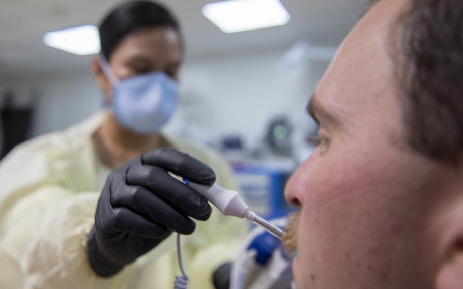 Navy Lt. Gail Evangelista, a nurse assigned to Naval Hospital Rota, Spain, takes a patient's temperature at the Michaud Expeditionary Medical Facility at Camp Lemonnier, Djibouti, April 16, 2020.