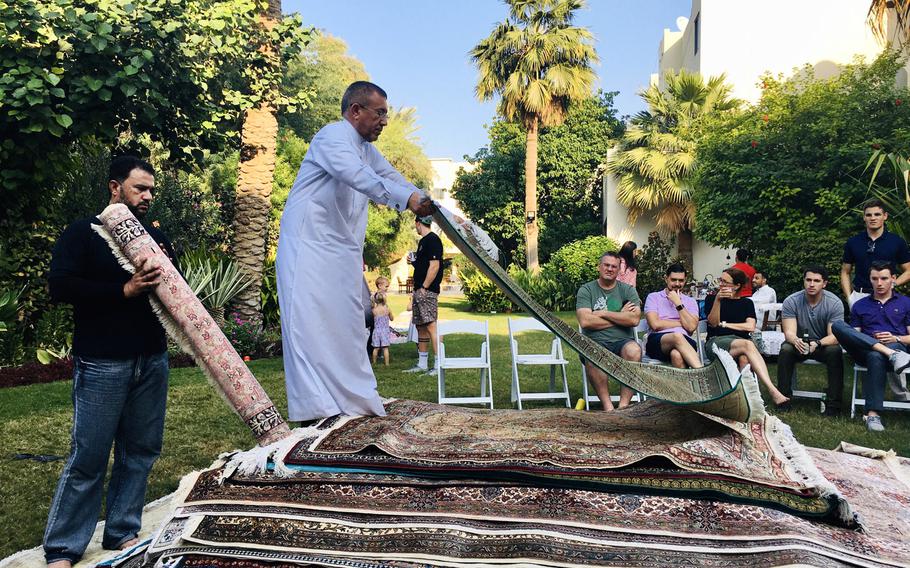 Mohammed Abdu Al-Omari rolls out a carpet during a ''rug flop'' event in Bahrain, hosted by U.S. Navy Cmdr. Joe Zerby and his wife, Jill.