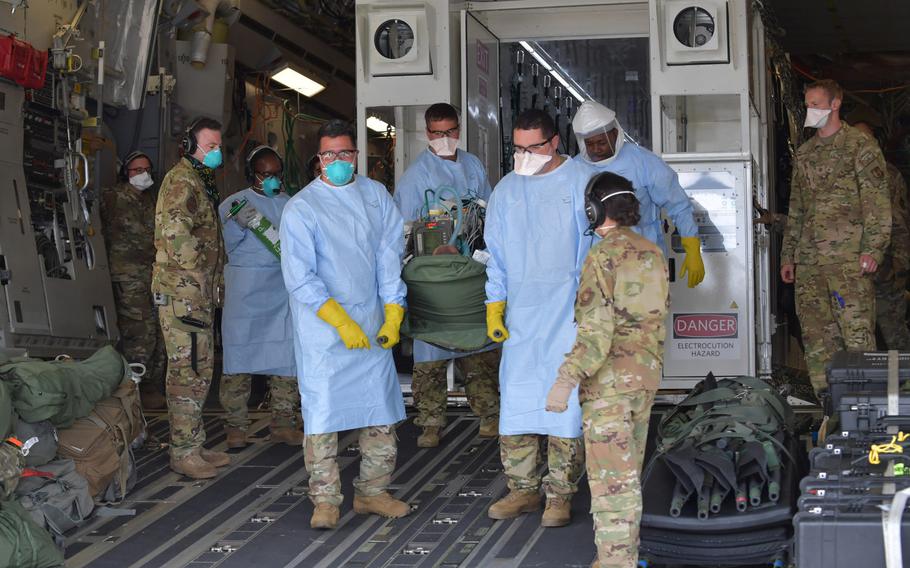 Airmen assigned to the 313th Expeditionary Operations Support Squadron transfer a coronavirus patient following the first operational use of the Negatively Pressurized Conex to transport 12 patients aboard a C-17 Globemaster III aircraft at Ramstein Air Base, Germany, July 1, 2020.