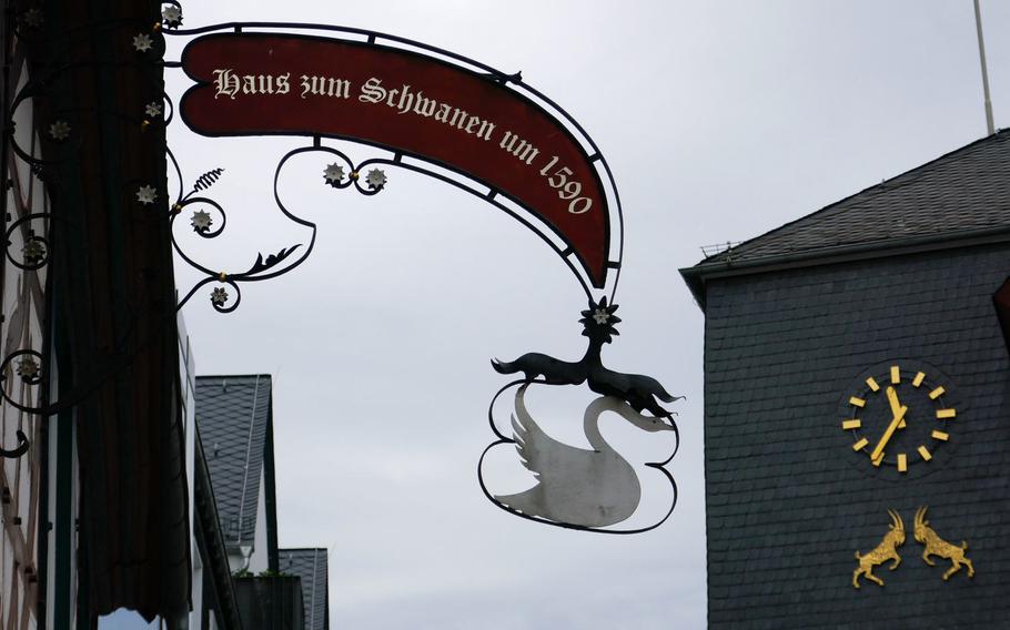 The Haus zum Schwanen is a beautiful late 16th-century half-timbered house in Kastellaun, Germany. In the background is the city hall clock with two goats, the trademark of the town.