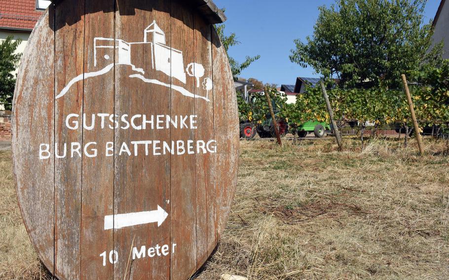 The bottom of a wine barrel points hikers along the Pfalz Wine Trail to a place to eat near castle ruins in the village of Battenberg, Germany.