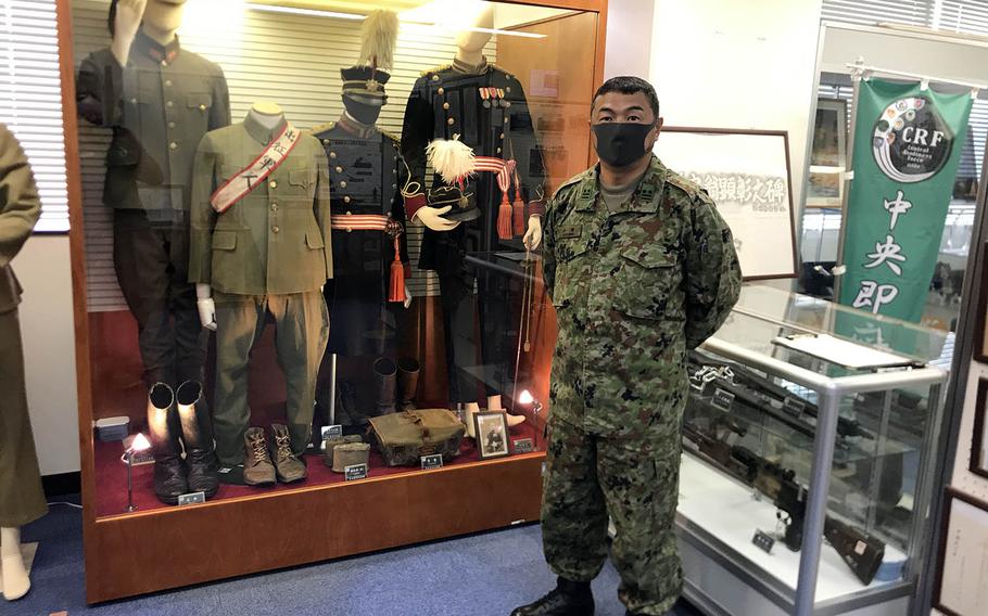 Lt. Col. Akira Ozawa of the Japan Ground Self-Defense Force poses with old Japanese Imperial Army uniforms and weapons inside a small museum at Camp Zama, Japan.