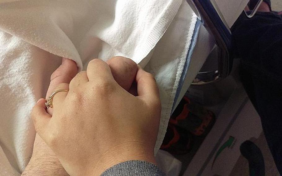 Rachel Moyers and her Air Force veteran husband, Matt, hold hands in the hospital.