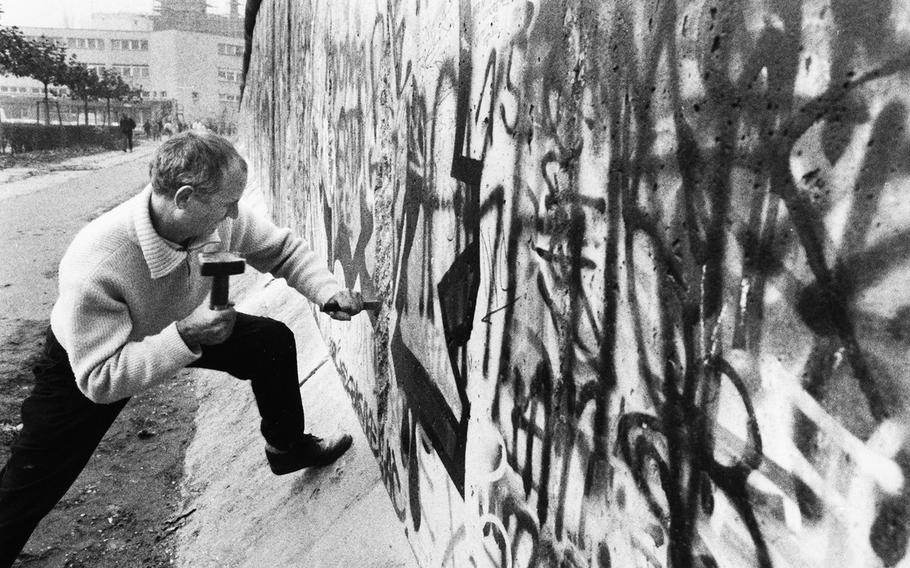 Berlin, November, 1989: A souvenir hunter chips away at the edges of a seam in the recently-breached Berlin Wall.