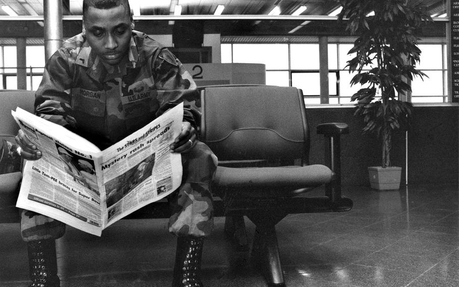 GI reading a copy of the Stars and Stripes European edition at what is to believed to be the Rhein-Main Air Base passenger terminal.