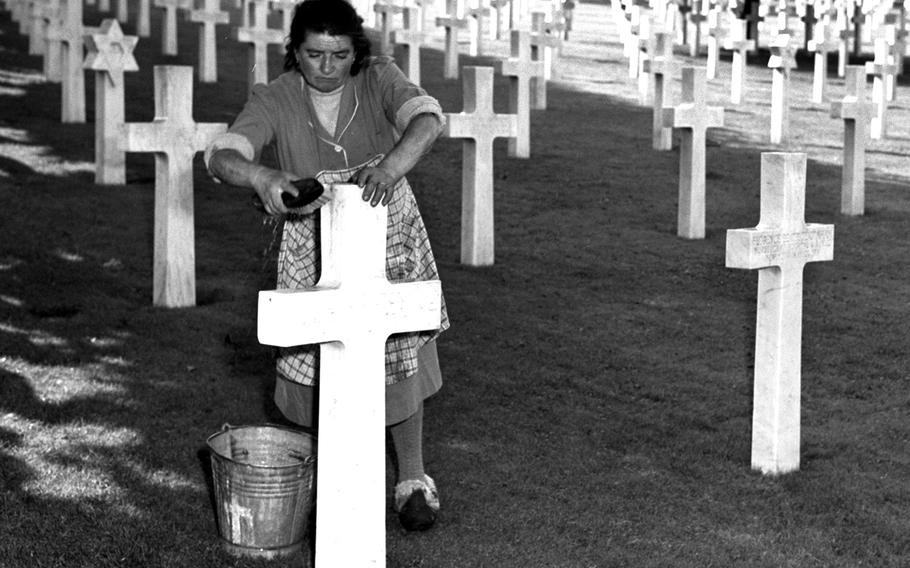 A woman cleans one of the grave markers in the military cemetery at Suresnes, just outside of Paris, where a ceremony was held to to dedicate a memorial to fallen U.S. servicemembers from World War II, September 1952.