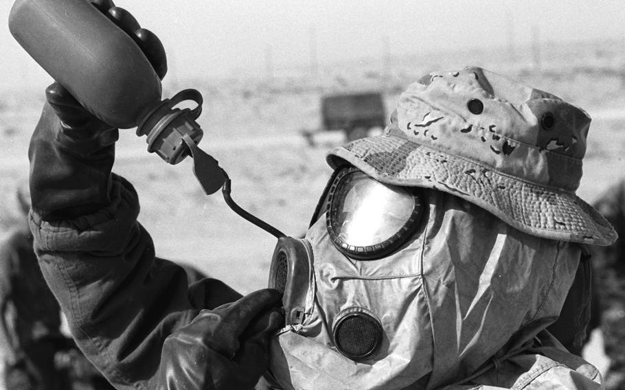 A U.S. Marine taking part in a chemical decontamination exercise in the weeks before the Gulf War gets some relief from the heat of his protective gear in the Saudi Arabian desert in November 1990.