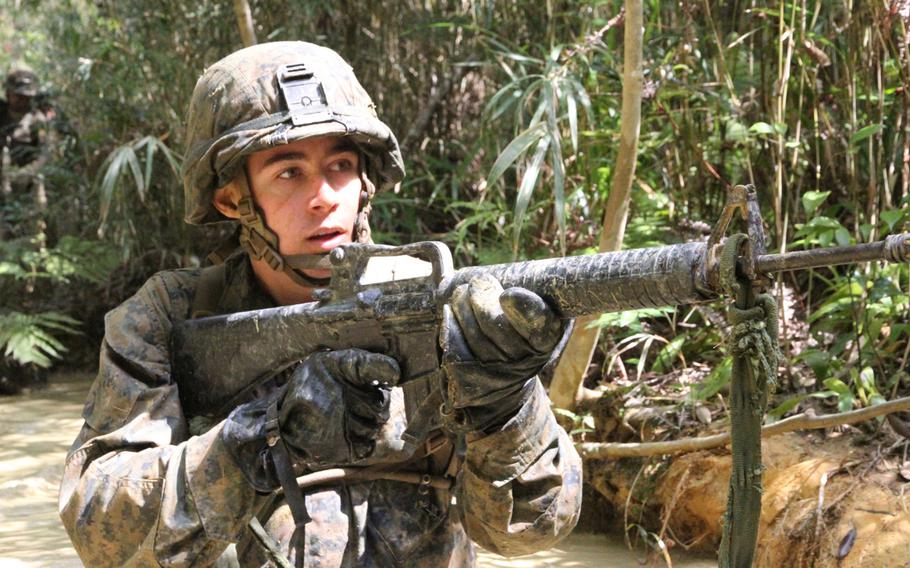 Lance Cpl. Kyle Littell wades through the waist deep ''peanut butter''' mud during the Jungle Warfare Training Center's E-Course in March 2015.