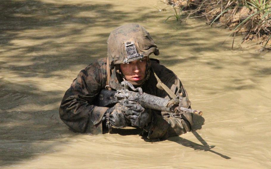 Lance Cpl. Andrew Luna wades through muddy water during Jungle Warfare Training on Okinawa in March 2015. Luna, who was nearly finished with Marine Officer Candidate School when he broke his arm in 2011, decided to enlist in the Corps to 2013. He still wants to be an officer, but ''you can lead enlisted men a lot better knowing what they go through,'' he says.