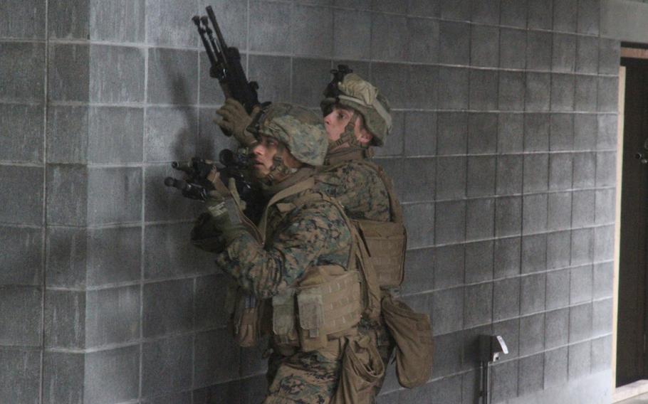 Lance Cpl. Andrew Luna, left, carefully moves into an unsecured building teeming with enemies during urban assault training at Camp Fuji's MOUT town in April. He is covered by Lance Cpl. James Spooner. Luna, who was nearly finished with Marine Officer Candidate School when he broke his arm in 2011, decided to enlist in the Corps to 2013. 
 
