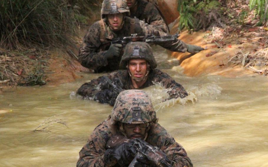 Marines from Company I's weapons platoon enter a pool of murky jungle water during the Jungle Warfare Training Center's E-Course in March.

