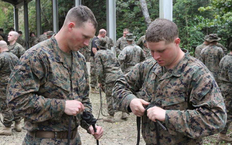 Then Cpl. Donald Horn, now a sergeant, left, watches Lance Cpl. Jacob Mathes as he ties a knot during training at the Jungle Warfare Training Center in March.