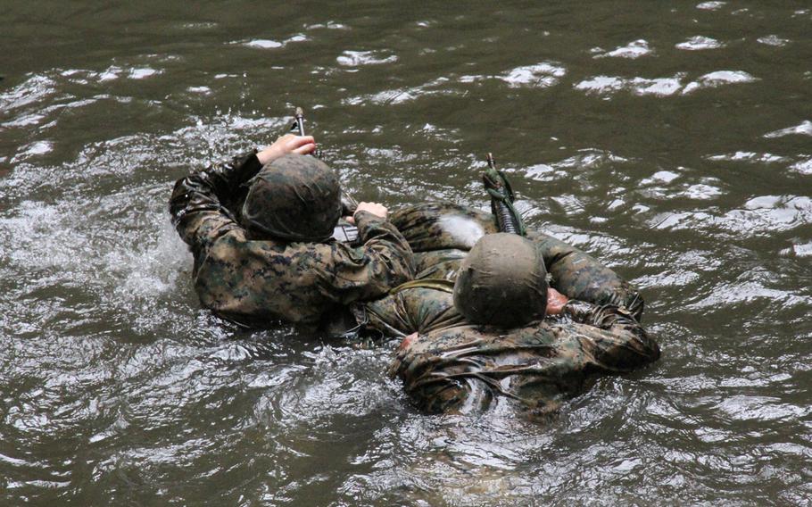 Third Platoon Marines traverse a jungle pool, rifles at the ready, using their packs and poncho liners to make an impromptu raft during jungle warfare training in Okinawa in March 2015.

