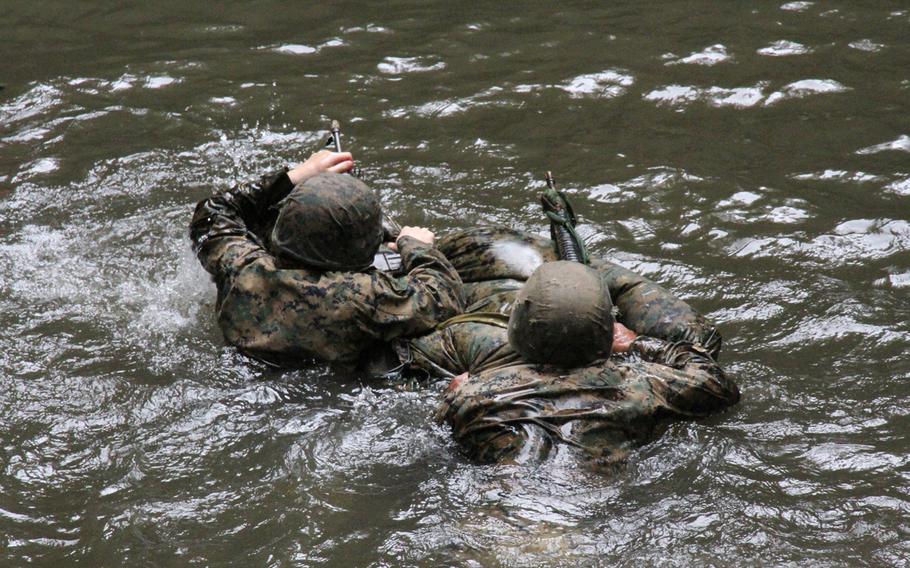 Third Platoon Marines traverse a jungle pool, rifles at the ready, using their packs and poncho liners to make an impromptu raft during jungle warfare training in Okinawa in March 2015.