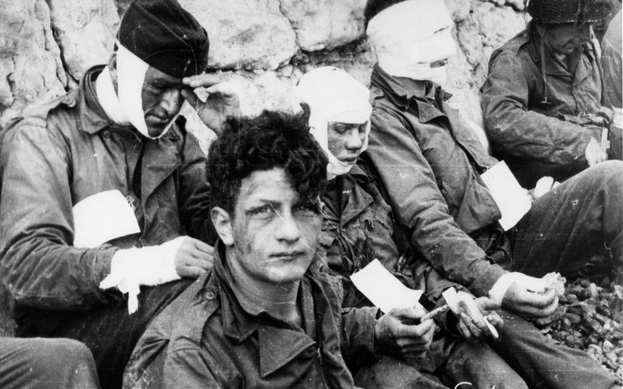 Wounded men of the 3rd Battalion, 16th Infantry Regiment, 1st Infantry Division, receive cigarettes and food after they had stormed Omaha beach on D-Day, June 6, 1944.  Photograph from the Army Signal Corps Collection in the U.S. National Archives.