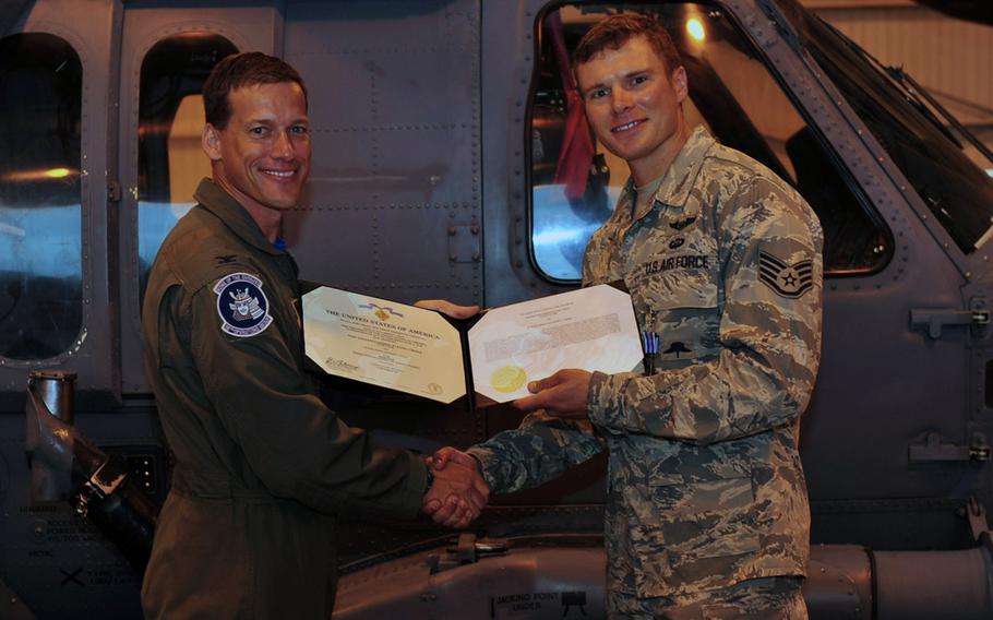 U.S. Air Force Col. Peter Milohnic, 18th Operations Group commander, presents Staff Sgt. Zach Hoeh, 31st Rescue Squadron pararescueman, with the Distinguished Flying Cross with valor, Kadena Air Base, Japan, Aug. 1, 2014. Hoeh was awarded the DFC with valor for acts of heroism during a deployment to Afghanistan in 2011.