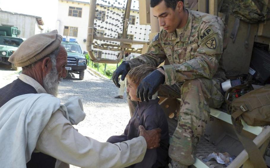 Sgt. Sean T. Ambriz, a military policeman who underwent medical training prior to deploying to Afghanistan, checks out an Afghan child during a mission in September 2011. 