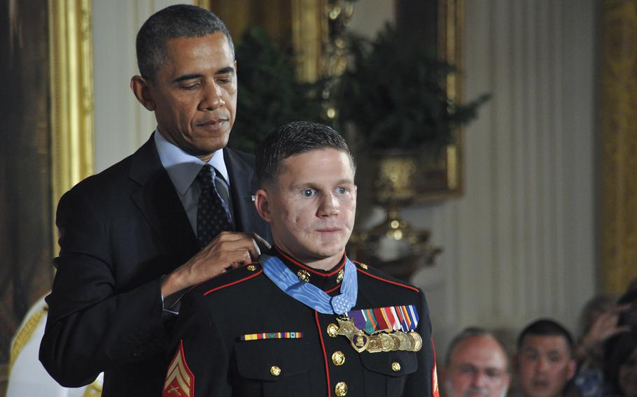 Obama places a medal around the neck of a Marine in uniform.