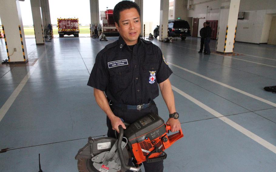 Kadena Air Base firefighter Tsuyoshi Taira shows off a K-12 fire rescue saw like the one used to penetrate over a foot of reinforced concrete and rebar to rescue two airmen trapped in a flooded building last year. The saw helped the first responders make some progress in freeing the airmen, but they were eventually forced to use hand tools after the belt disintegrated. Twenty-six U.S. servicemembers and Japanese civilian first responders were honored in September for their efforts.