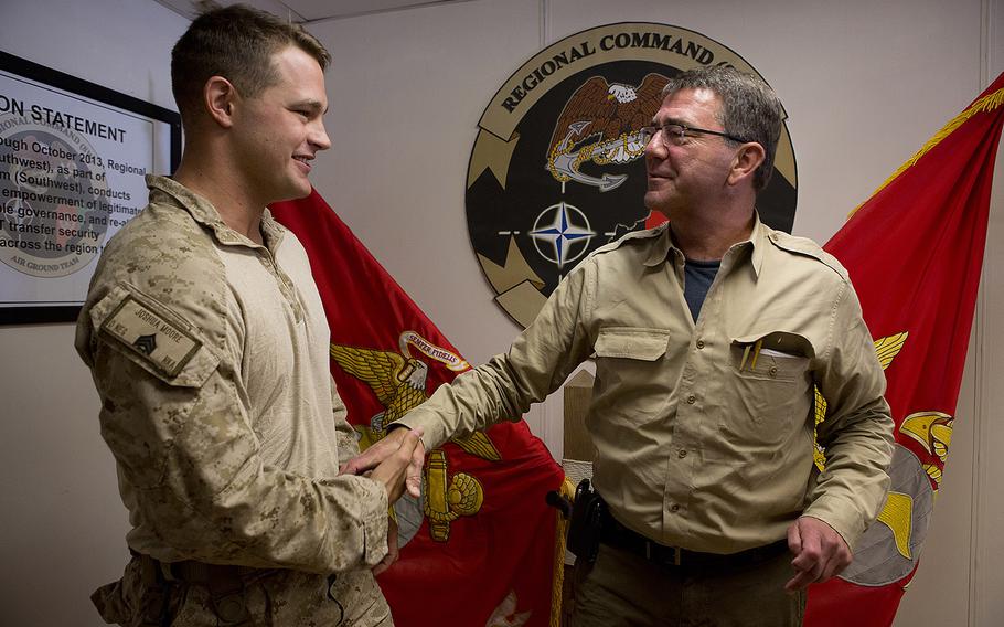Marine Corps Sgt. Joshua Moore, left, shakes hands with then-Deputy Secretary of Defense Ashton B. Carter at Camp Leatherneck, Afghanistan, on Sept. 13, 2013.