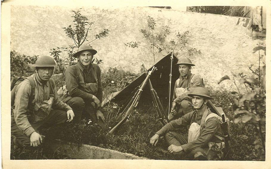 Soldiers resting in grass by pup tent (Sgt. William Shemin shown kneeling second from the left).