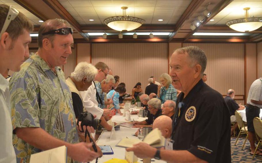 Medal of Honor recipient Walter Marm, Jr., talks with Andrew and Mike Elliott during a book signing at the Hale Koa Hotel in Honolulu on Oct. 6, 2012. The signing was the final public event of the 2012 Medal of Honor Convention. The reunion of 52 medal recipients is thought by organizers to be the largest ever gathering of its kind.