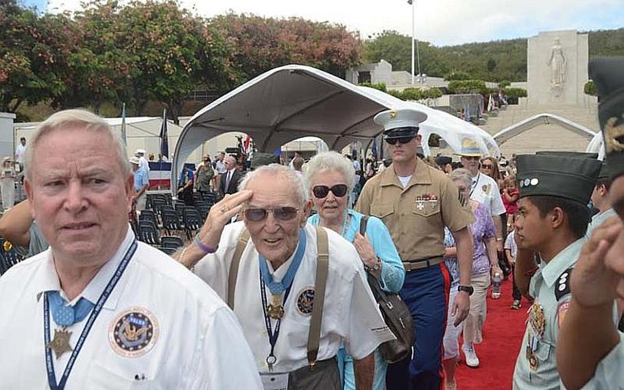 Vietnam-era Medal of Honor recipient George 'Bud' Day, center, salutes as he walks down a red carpet at the National Cemetery of the Pacific in Honolulu on Oct. 3, 2012.