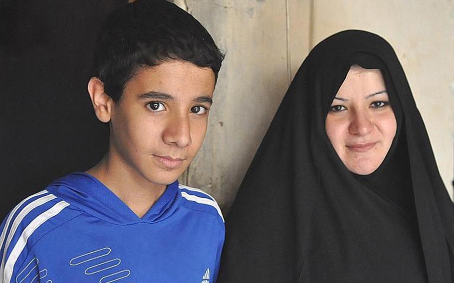 Aklas Farhood, whose husband was killed in a Baghdad bombing, stands with her son Gafor, 12,  in front of the tiny room that they share with Gafor's older brother.