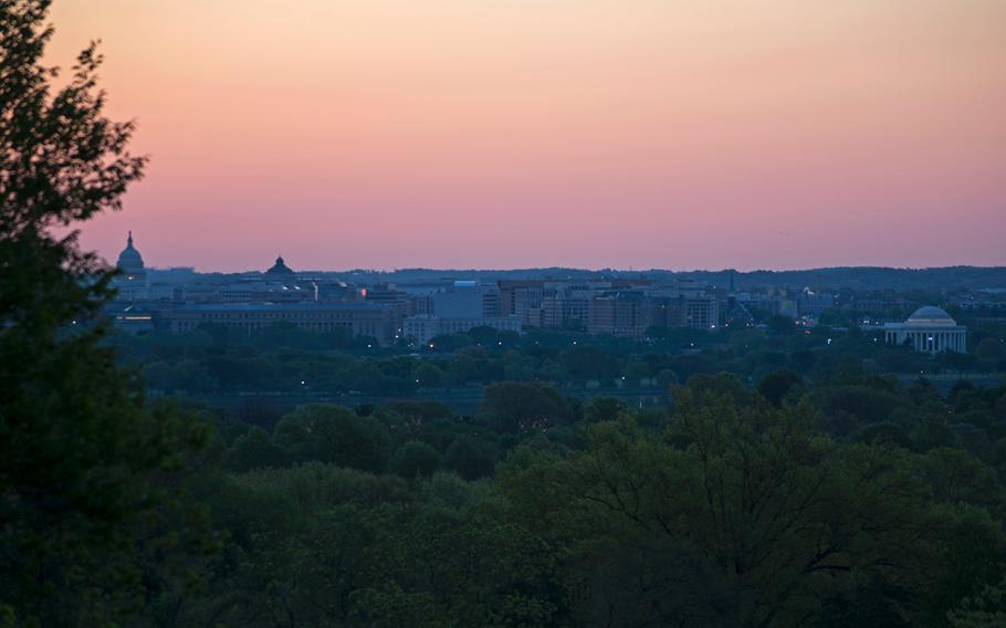The Thomas Jefferson Memorial and the Capitol Building are bathed in pinks and yellows as the sun starts to rise on May 4, 2014, as seen from Arlington National Cemetery. 