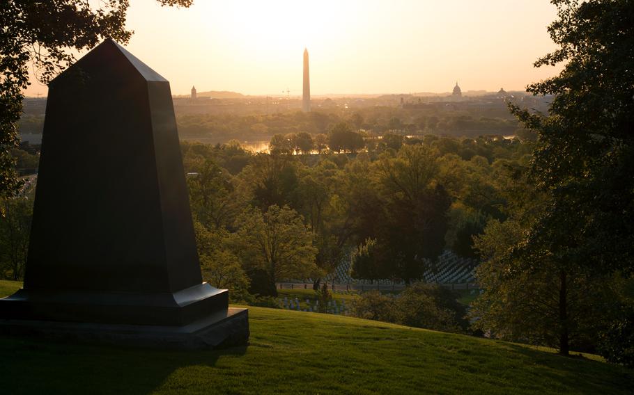Arlington National Cemetery is cast in a pink and yellow hues as the sun rises on May 4, 2014. In the distance is the Washington Monument and the Capitol Building. 