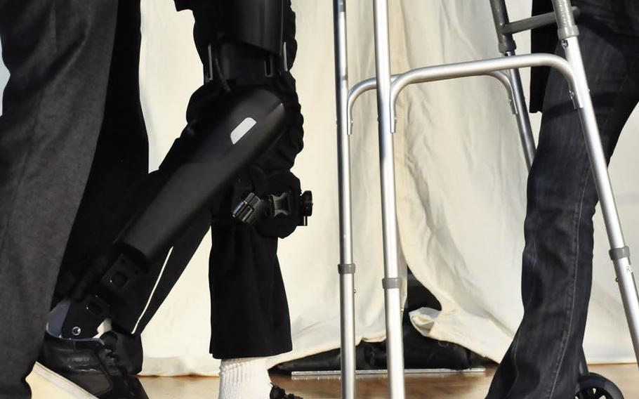 Trevor Greene, a former Canadian soldier who suffered a brain injury during an attack in Afghanistan in 2006, walks with a robotic exoskeleton, Sept. 17, 2015, at Simon Fraser University in British Columbia. The device has metal rods that run down the sides of his legs and insoles that are placed inside his shoes. Small motors at the hip and knee help propel him forward.