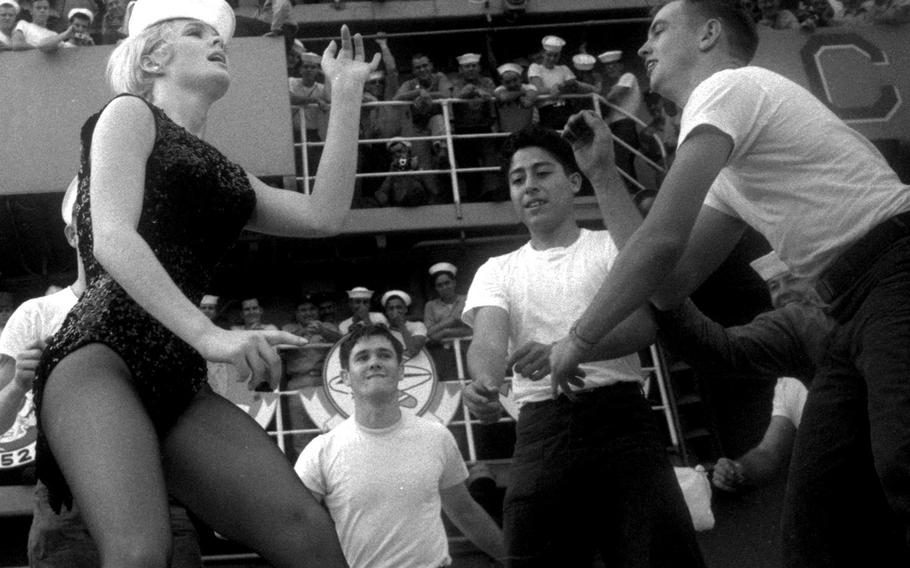 December, 1965: Singer-actress Joey Heatherton dances with sailors on the deck of the USS Ticonderoga, off the coast of Vietnam, during the annual Bob Hope Christmas tour of the Far East.