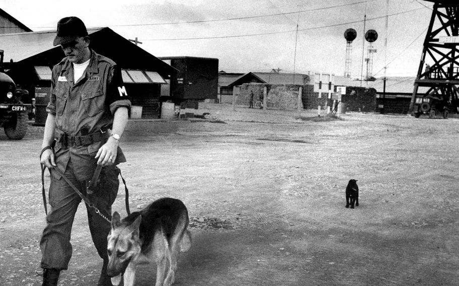 November, 1965: A military policeman and his dog are being followed as they patrol the tiny Vinh Long airfield, home of the U.S. Army's 114th Aviation Company, in South Vietnam's Mekong Delta region.
