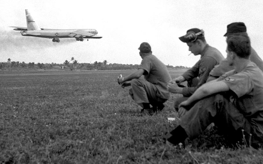November, 1965: Their work done for the time being, members of the ground crew at Andersen Air Force Base, Guam, watch as a B-52 takes off on a bombing mission over suspected Viet Cong strongholds in South Vietnam.