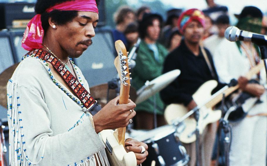 Jimi Hendrix playing his guitar during his set at the Woodstock Music and Art Fair. Playing with Jimi Hendrix is Billy Cox (wearing a turban).