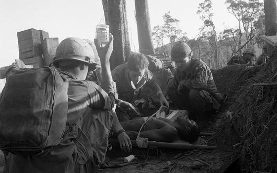 142p av          The 3rd Battalion, 187th Infantry Regiment of the 101st Airborne Division on the day they took the mountain, west of A Shau Valley, called Dong Ap Bia, or Hamburger Hill. [jc]; One soldier holds an IV bottle high up in the air as a medic puts bandages around a chest wound of an unidentified African-American soldier. Men of the 3rd Battalion, 187th Infantry Regiment, 101st Airborne Division have been trying to take the bomb-scarred, blood-soaked mountaintop - called Hamburger Hill - from North Vietnamese forces. [cg]