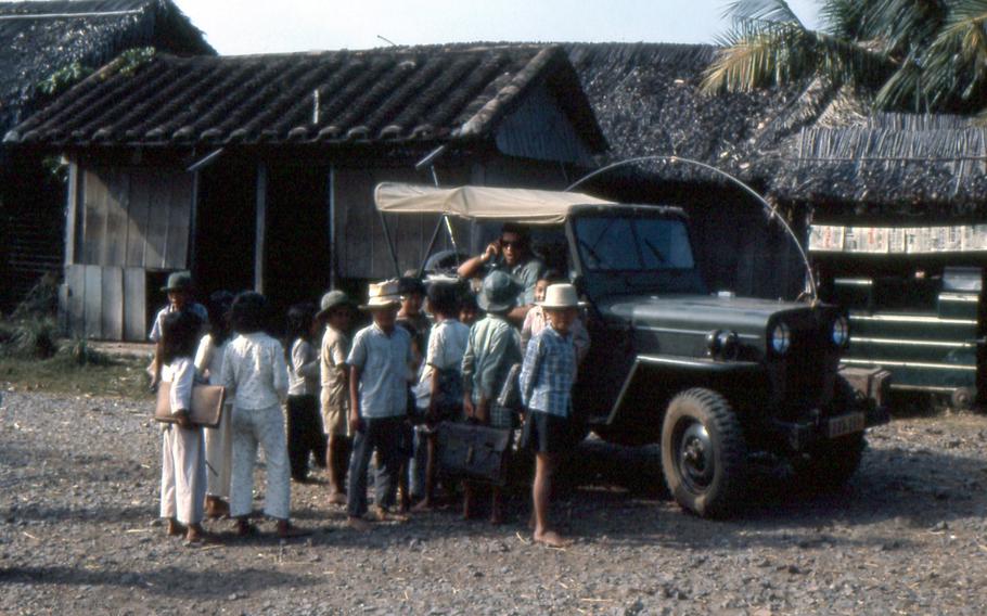 As described by Austin Miller: "Kids stopping by to talk to Co Van My (American adviser - Lt Kiger) on way to school. Long Hoa Village 1965."