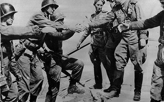 This posed photo of the Americans soldiers, left, meeting the Russians on the Elbe River at Torgau, Germany, April 26, 1945, was one of the most famous photographs of World War II. It was posed and taken by Allan Jackson, an International News Service war correspondent at the  time.

(No credit given, but similar photo is credited to AP)