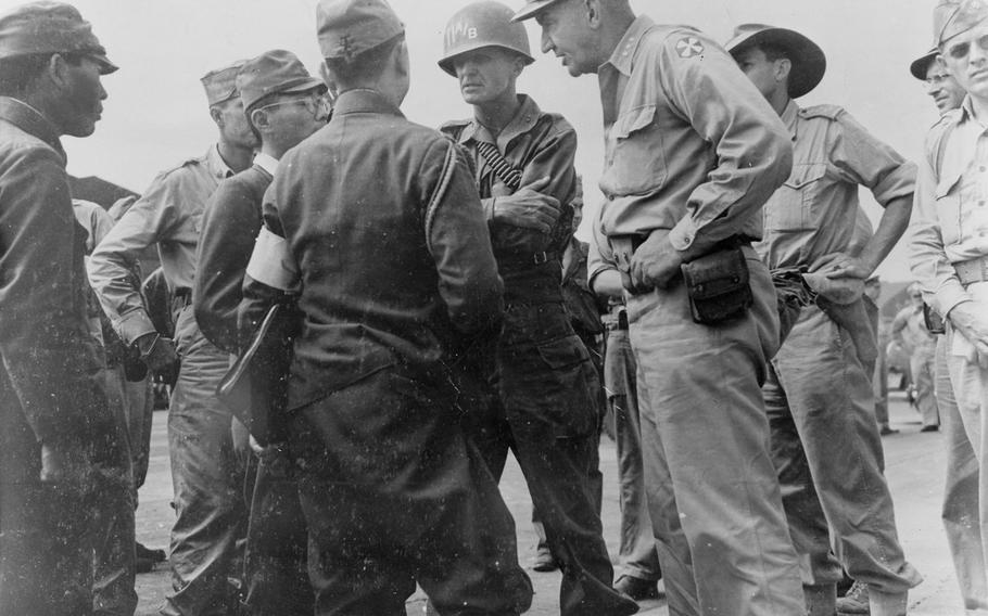 Maj. Gen. Joseph M. Swing, and Lt Gen. Robert L. Eichenberger, speak with Japanese Lt. Gen. Seizo Arisue and 1st Lt. Sadado Otake at the Atsugi Airdrome near Tokyo on Aug. 30, 1945, days before the formal surrender.