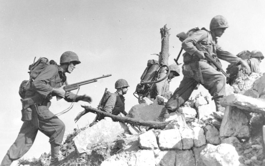 Marines hurdle a stone wall as they drive across Okinawa on April 1, 1945, the first day of the Battle of Okinawa.
