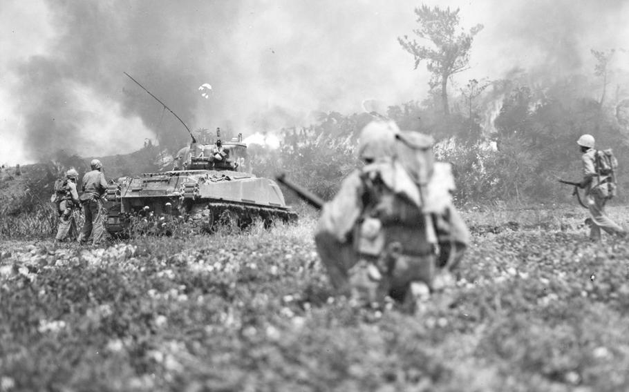 Marine riflemen movie up behind flame-throwing tank on May 23, 1945, during the Battle of Okinawa.