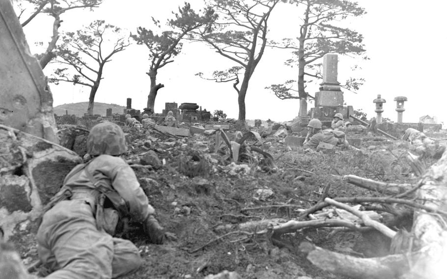 U.S. Marines are pinned down behind gravestones by enemy sniper fire as they move their way through ''Cemetery Ridge," on June 1, 1945, during the Battle of Okinawa.