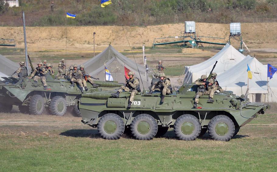 Ukrainian soldiers ride on an armored personnel carrier during a mock attack on a forward operating base at Exercise Rapid Trident near Yavoriv, Ukraine, Friday, Sept. 19, 2014.