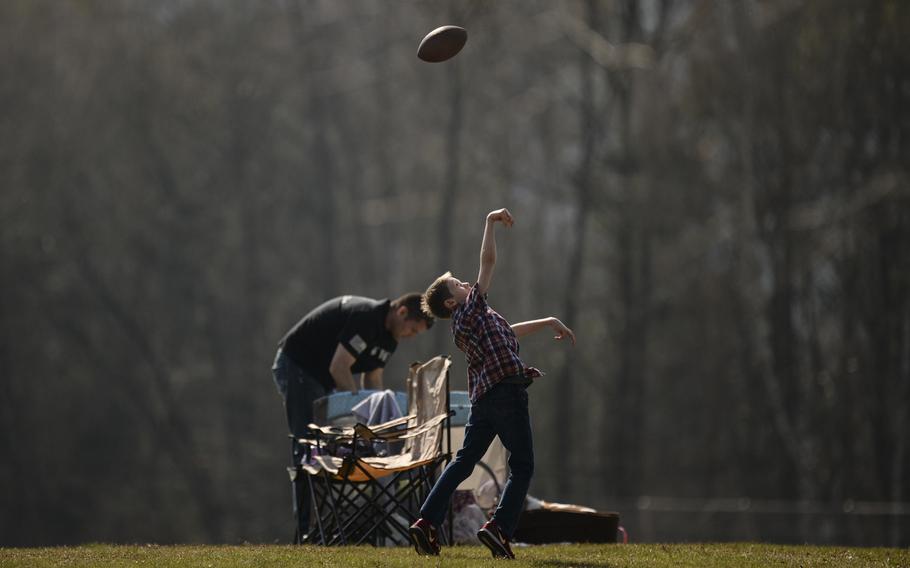 Kobe Mammann, 9, tosses a football between innings as he and his stepfather, Justin DuBose, watch his sister Riley DuBose of Kaiserslautern play in a softball doubleheader against Baumholder on March 29, 2014, in Kaiserslautern, Germany.
