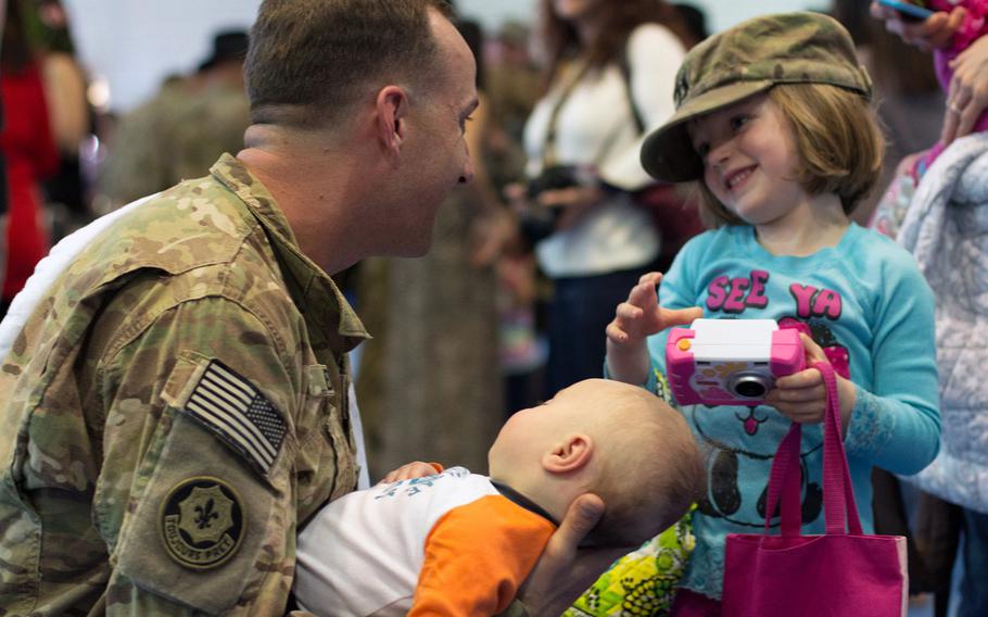 Capt. Riley Redus greets his daughter, Sierra, while holding his newborn son, Caleb John, for the first time after returning from a nine-month deployment to Afghanistan with the 2nd Cavalry Regiment on April 7, 2014.