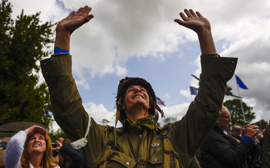 A World War II re-enactor waves at an MC-130 overhead during a 70th anniversary D-Day commemoration at the 9th Air Force Memorial at Picauville, France, June 5, 2014.